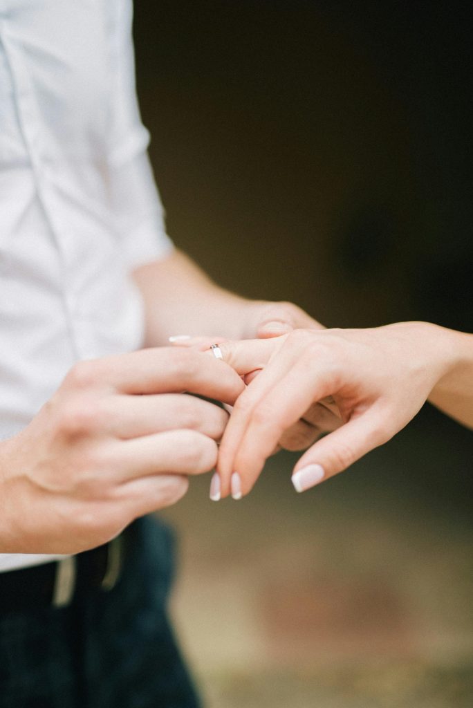 Close-up of a couple exchanging engagement rings, symbolizing love and commitment.